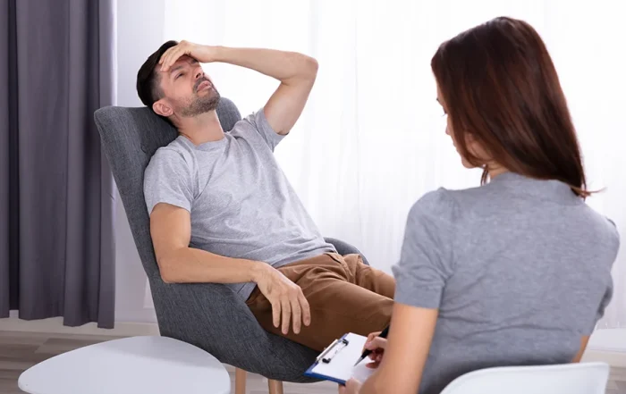 Man showing distress during a counseling session with a therapist, discussing post acute withdrawal symptoms and coping strategies